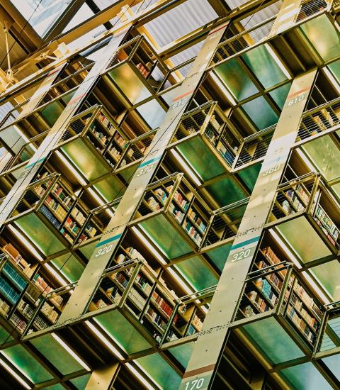 Stacks of books in a library with metallic shelving